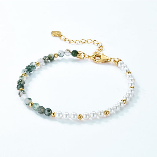 Gold - toned beaded bracelet: White pearls, green stones, gold spacers, chain extender with heart tag, white background.