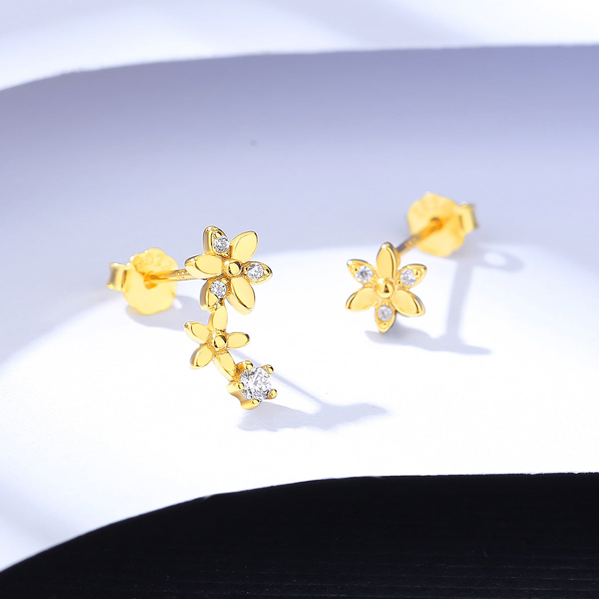 Gold earrings with Asymmetric floral design on a white background