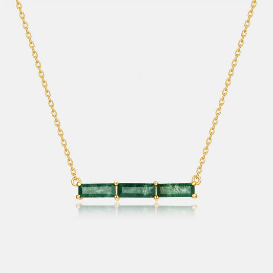 Gold - toned necklace: Horizontal bar pendant with three emerald - cut green stones on gray background.