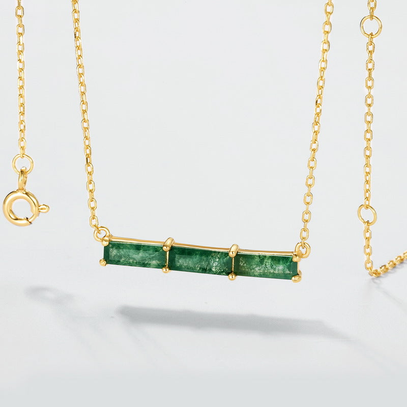 Gold - toned necklace: Horizontal bar pendant with three emerald - cut moss agate stones, isolated on white.