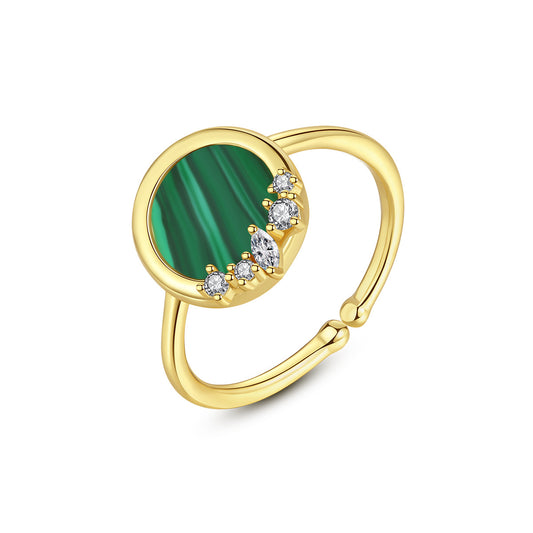 Like a slice of emerald forest captured in gold this open ring centers a round malachite stone, its vivid green bands paired with sparkling CZ accents. Set in 14K gold plated metal with a polished finish, the adjustable band fits comfortably on any finger. Light and easy to wear, it adds an Art Deco-inspired touch of nature’s charm to jeans or dresses alike—always a subtle yet striking statement.