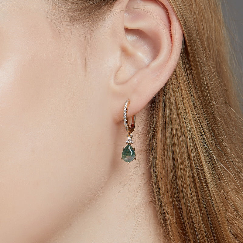 Close - up of gold hoop earring on a person: Teardrop moss agate pendant, crystal - encrusted band, showcasing elegant style