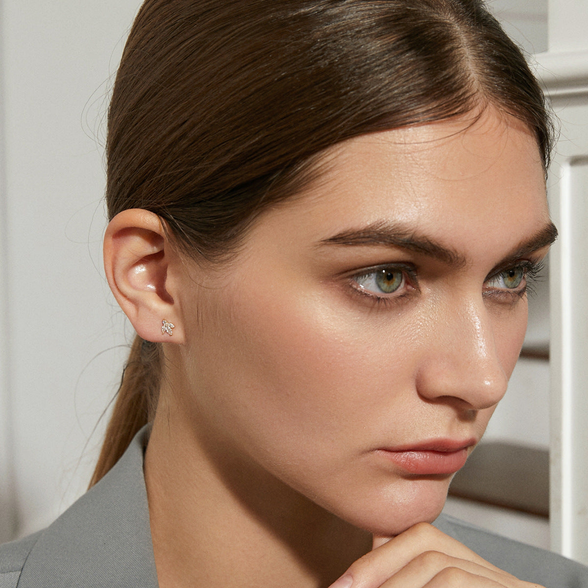 Close-up of a woman wearing a cubic zirconia earring with a neutral background
