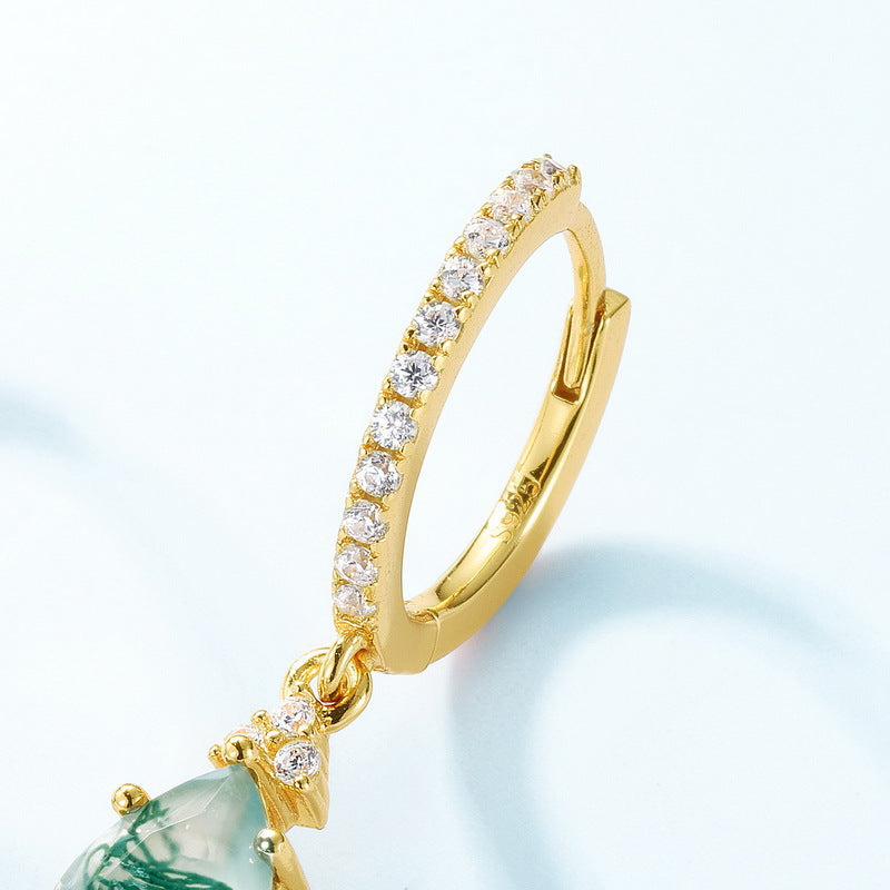 Close - up of gold hoop earring on a person: Teardrop moss agate pendant, crystal - encrusted band, showcasing elegant style.