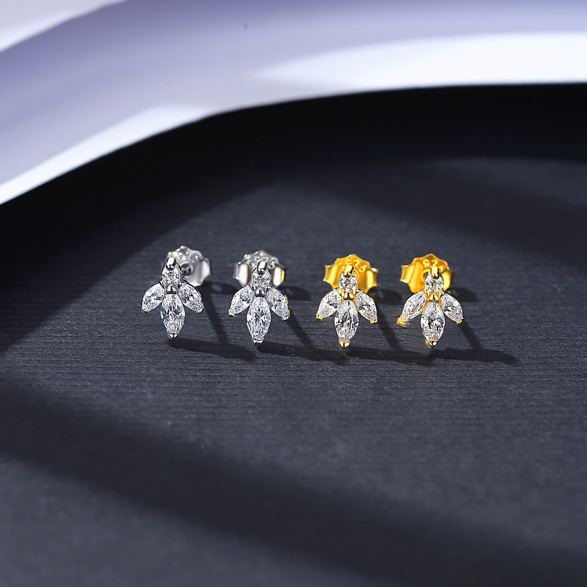 Pair of silver and gold flower-shaped earrings on a dark surface