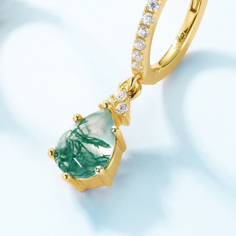 Gold hoop earring: Teardrop moss agate pendant with crystal accents, on a light background.