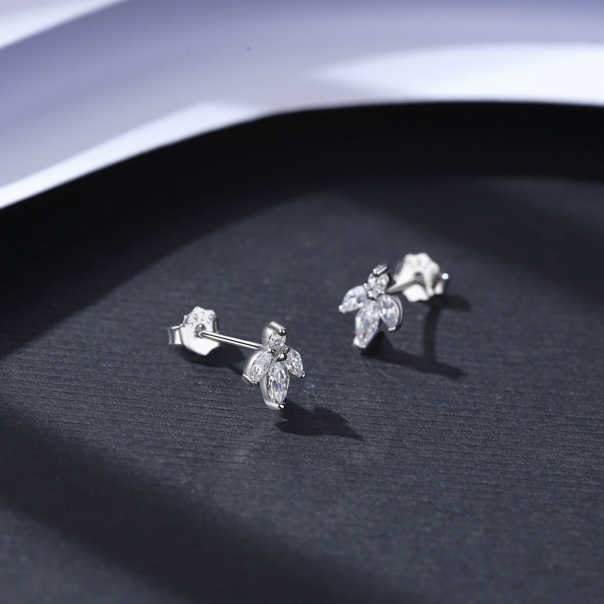 Silver earrings on a dark surface with a white background