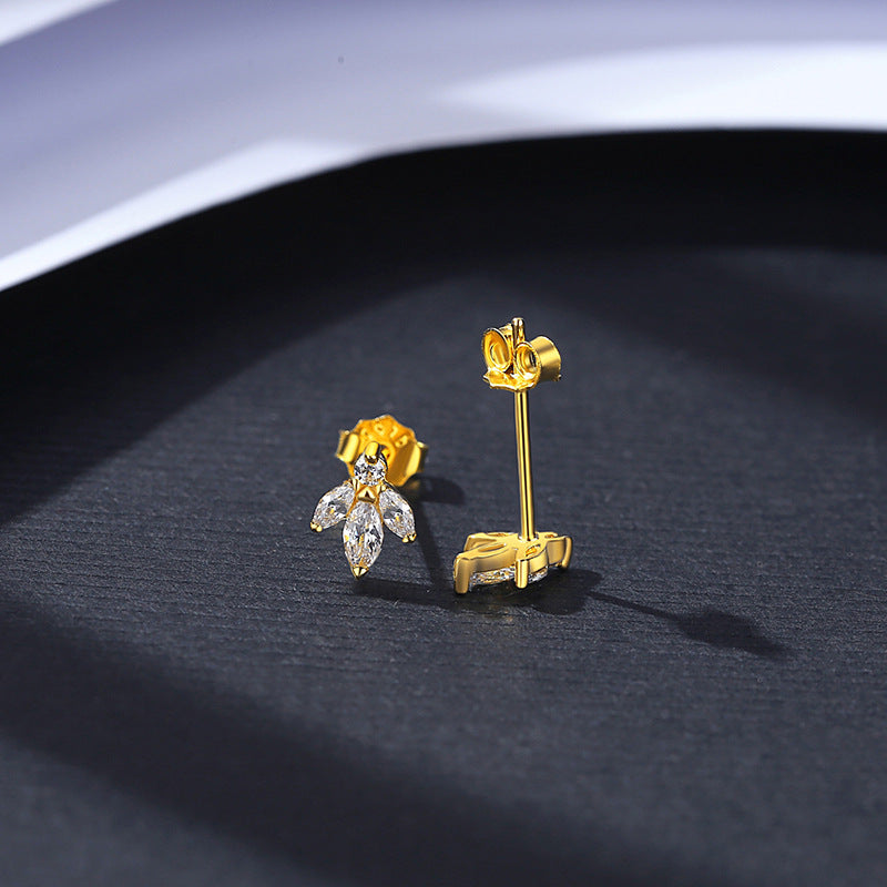 Gold dog-shaped earrings on a dark surface