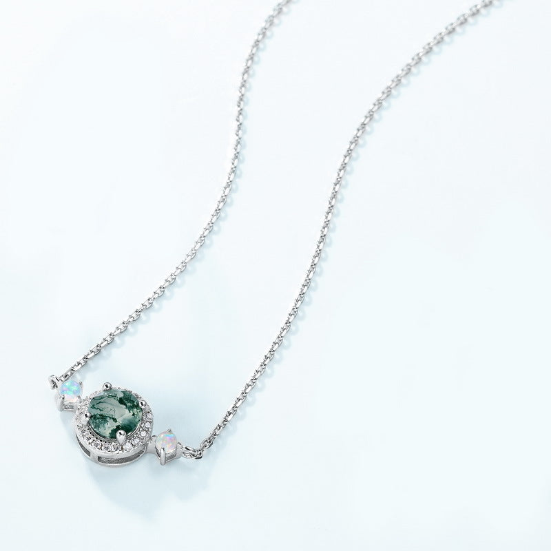 Silver - toned necklace: Circular moss agate pendant, crystal halo, opal - like accents, isolated on white.