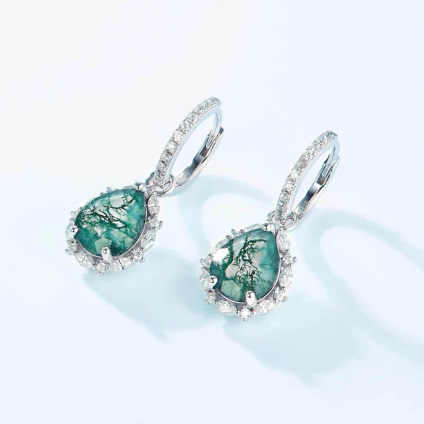 Silver - toned earrings: Teardrop moss agate, crystal halo, hoop design, isolated on white.