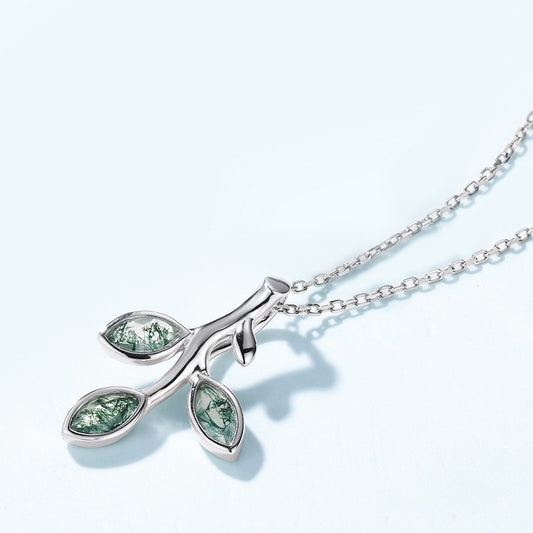 Silver - toned necklace: Branch - shaped pendant, three leaf - like settings with green moss agate, isolated on light blue
