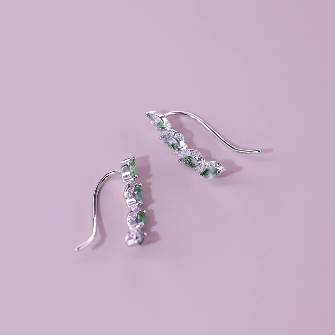Silver - toned earrings: Marquise moss agate stones, crystal accents, curved vine design, on a pink background.
