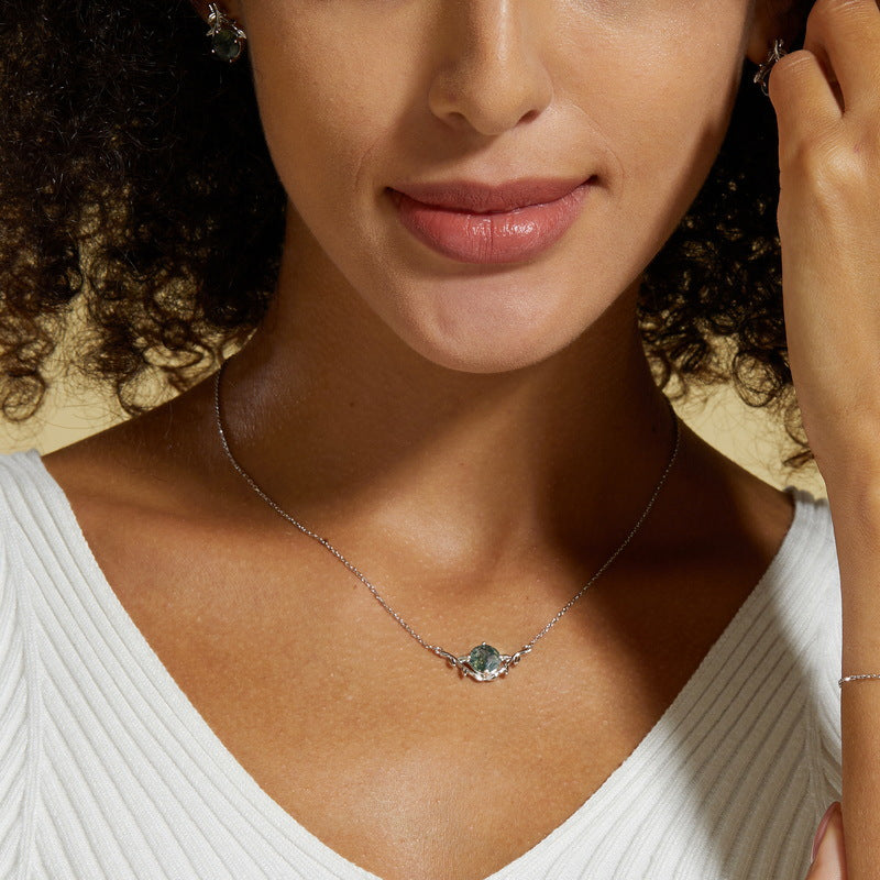 A person wearing a silver - toned necklace: Round moss agate pendant, leaf - shaped design, showcasing elegance.