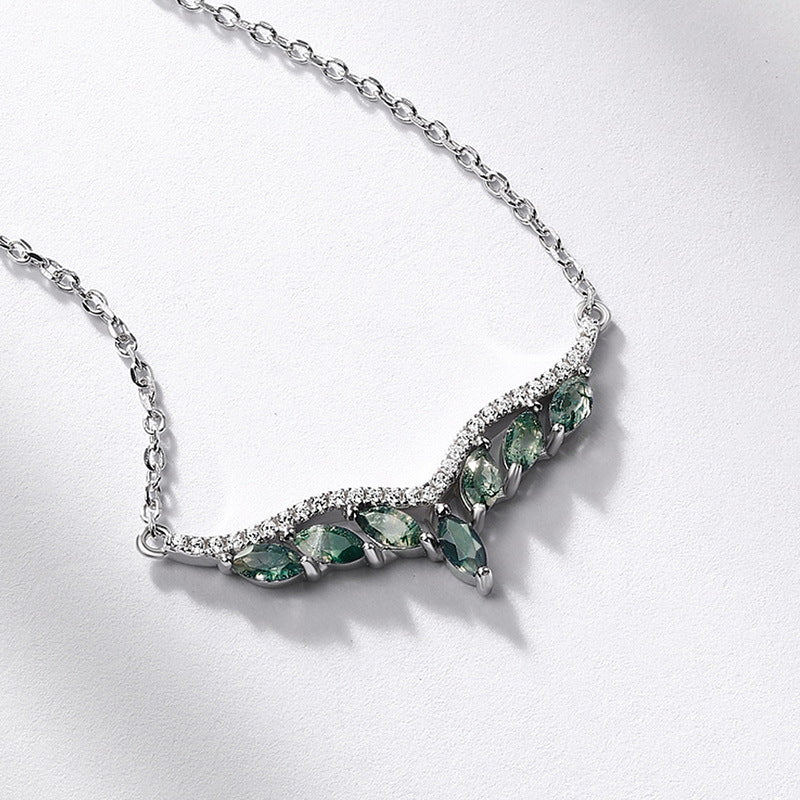Extreme close - up of silver - toned necklace pendant: V - shaped design, marquise moss agate stones, crystal accents, isolated on white, highlighting details.