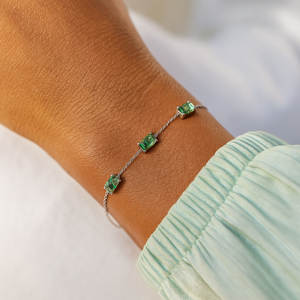A silver bracelet with three rectangular moss agate gemstones is worn on a person's wrist, shown against a white background and a light green sleeve.