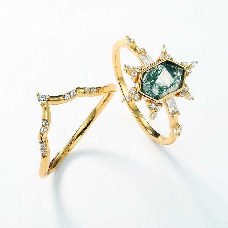 Gold - toned ring set: Hexagonal moss agate ring and geometric crystal - encrusted ring, isolated on white.
