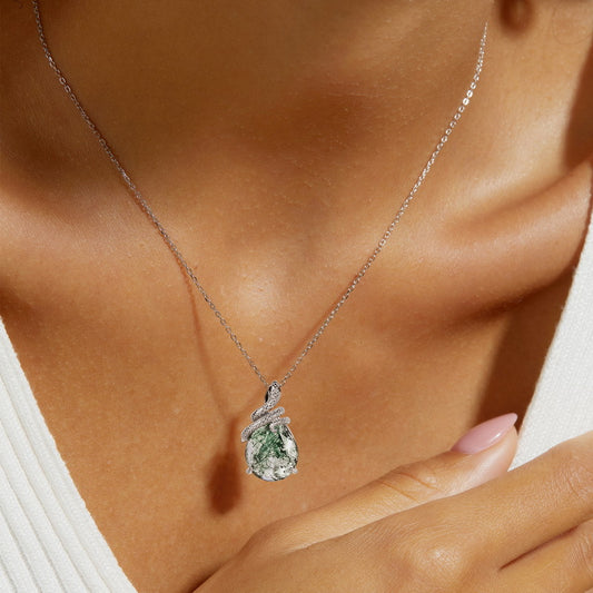 Silver - chained necklace with teardrop moss agate pendant wrapped by snake - shaped metal, worn on a person's neck, elegant daily accessory