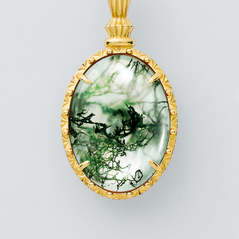 Gold - toned pendant: Oval moss agate stone, decorative frame, isolated on white.