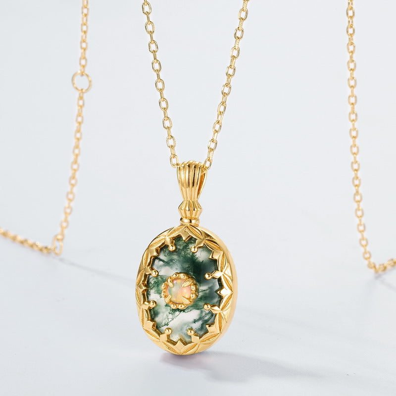 Gold necklace with a green stone pendant on a light gray background