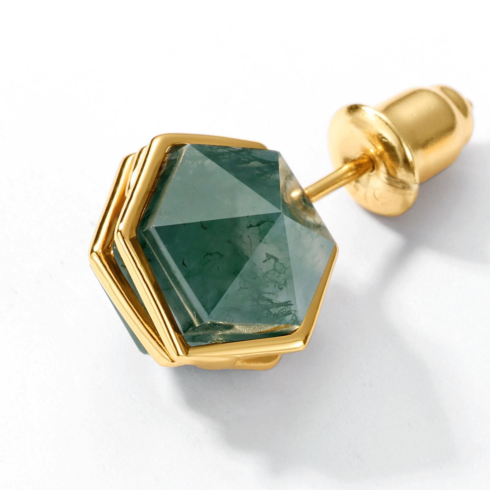 Extreme close - up of gold - toned stud earring: Hexagonal moss agate stone, geometric metal setting, isolated on a white background, emphasizing details.