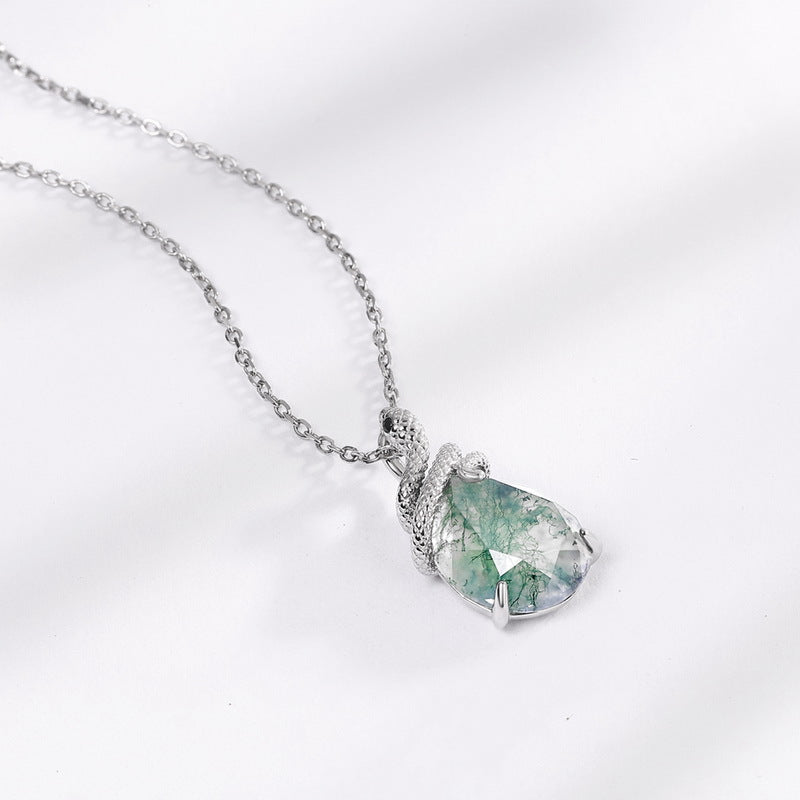 Close - up of silver necklace: teardrop moss agate pendant coiled by detailed silver snake, showcasing intricate design