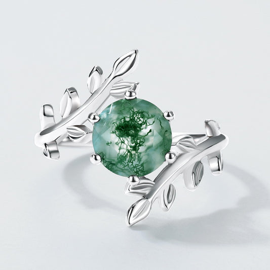 Silver ring featuring moss agate, leaf - branch band, close - up on light gray background, highlighting details
