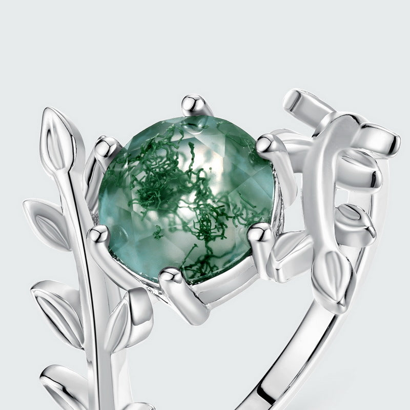 Silver ring with moss agate, leaf - shaped prongs, extreme close - up, emphasizing stone and metalwork