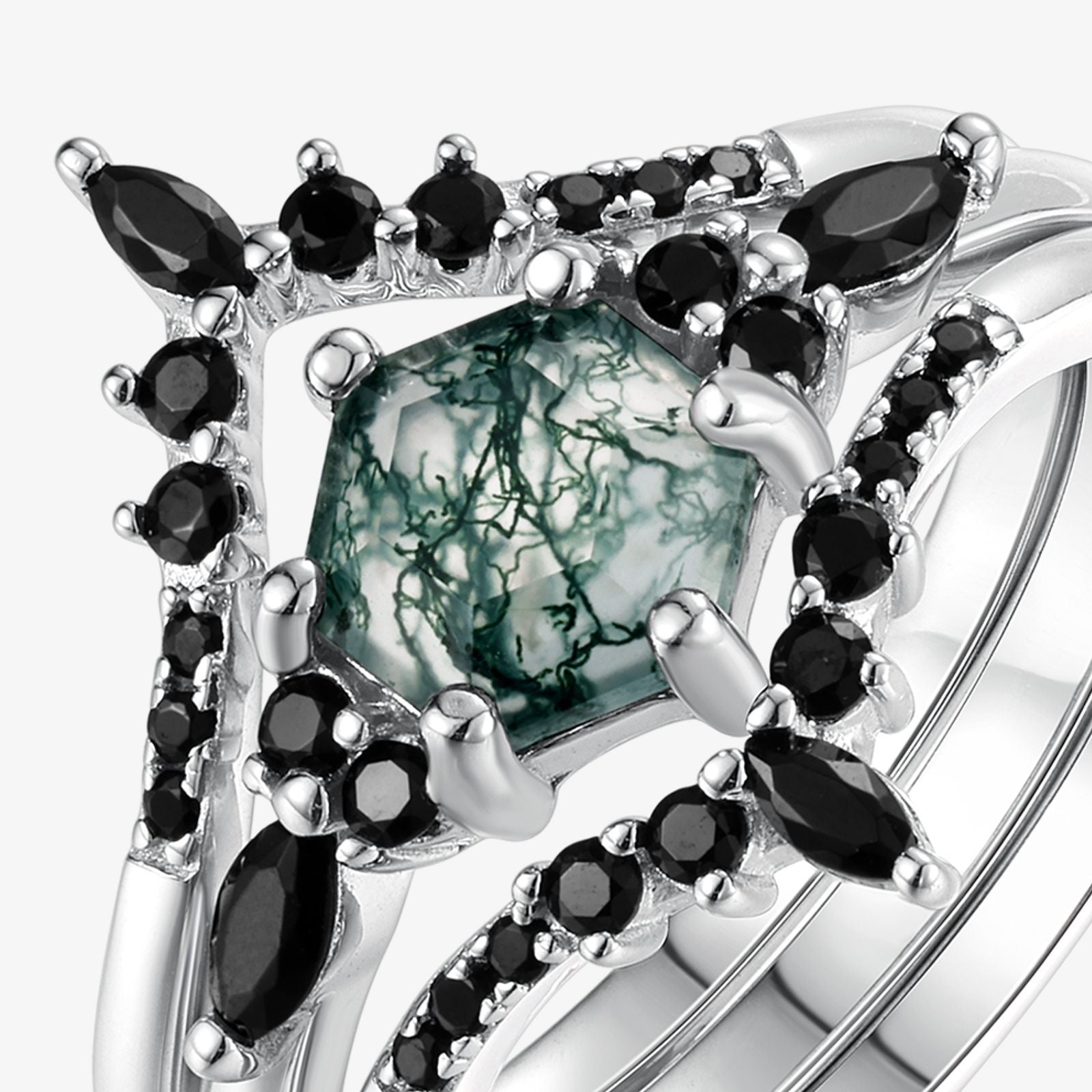 Extreme close - up of silver - toned ring set: Highlights the intricate patterns in the hexagonal moss agate, framed by black gemstones, isolated on white.