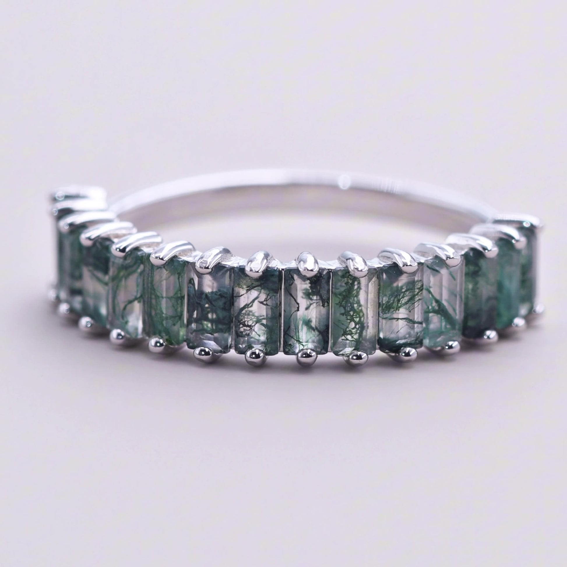 Silver ring: A row of rectangular moss agate settings, isolated on a light gray background, highlighting the unique stone patterns.