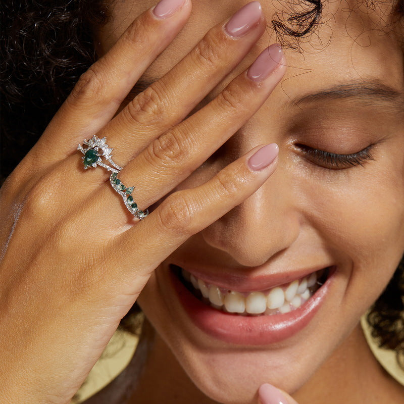 Hands wearing silver rings with moss agate and cubic zirconia, showcasing elegant designs for special occasions.