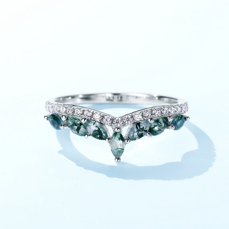 Silver V - shaped ring: Marquise moss agate stones, cubic zirconia - lined band, isolated on light blue background.