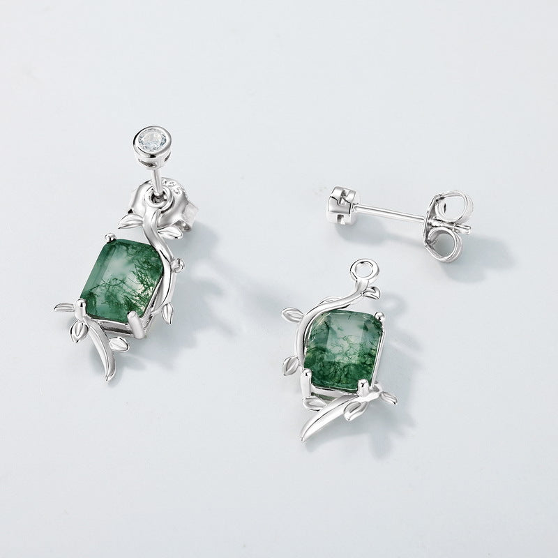 Silver earrings featuring moss agate, leaf - branch band, close - up on light gray background, highlighting details