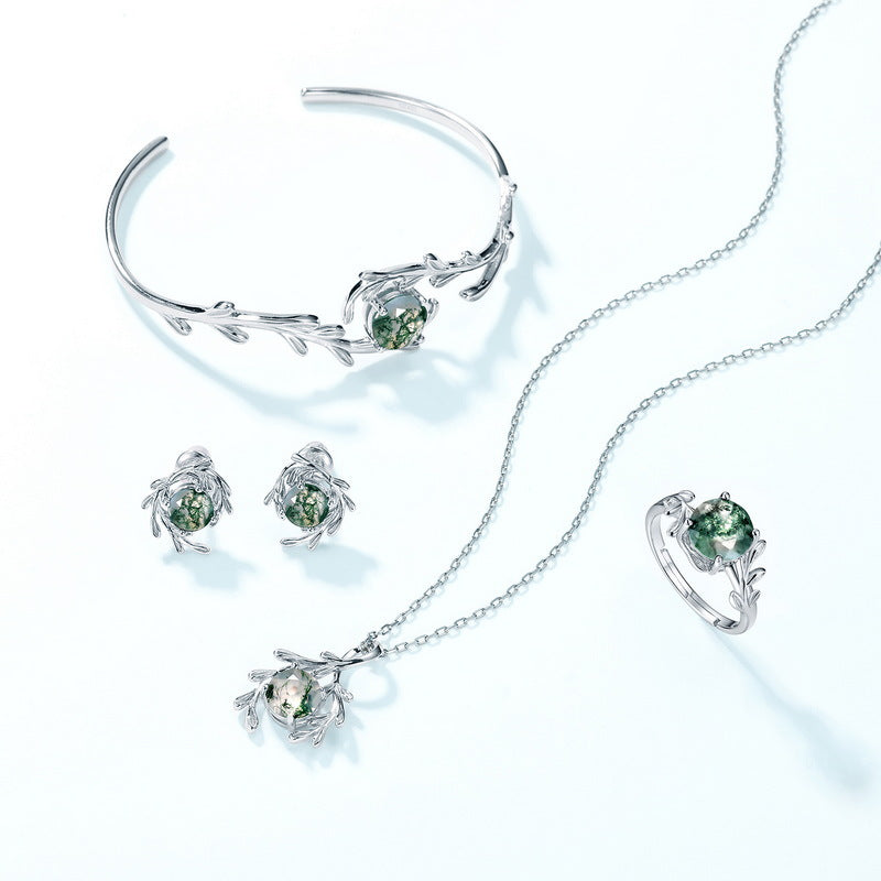 Silver - toned jewelry set: Includes a bracelet, earrings, necklace, and ring, all with leafy branch designs and moss agate stones, isolated on white.
