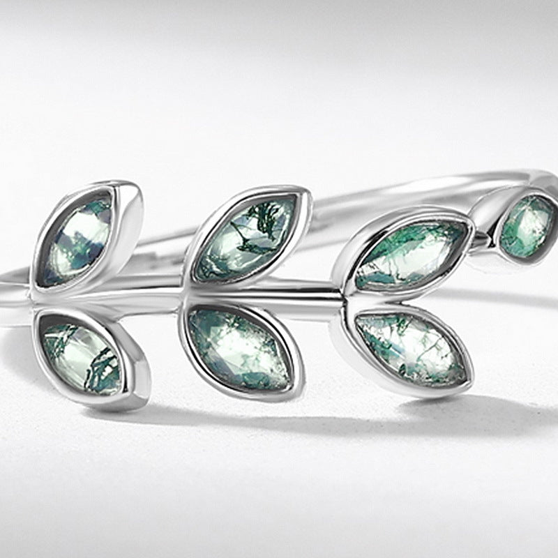 Silver ring with leaf - shaped moss agate settings, extreme close - up, highlighting stone patterns and metal details