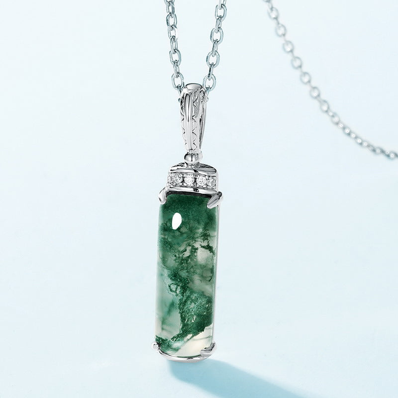 Silver necklace with rectangular moss agate pendant, cubic zirconia - topped bail, close - up on light blue background