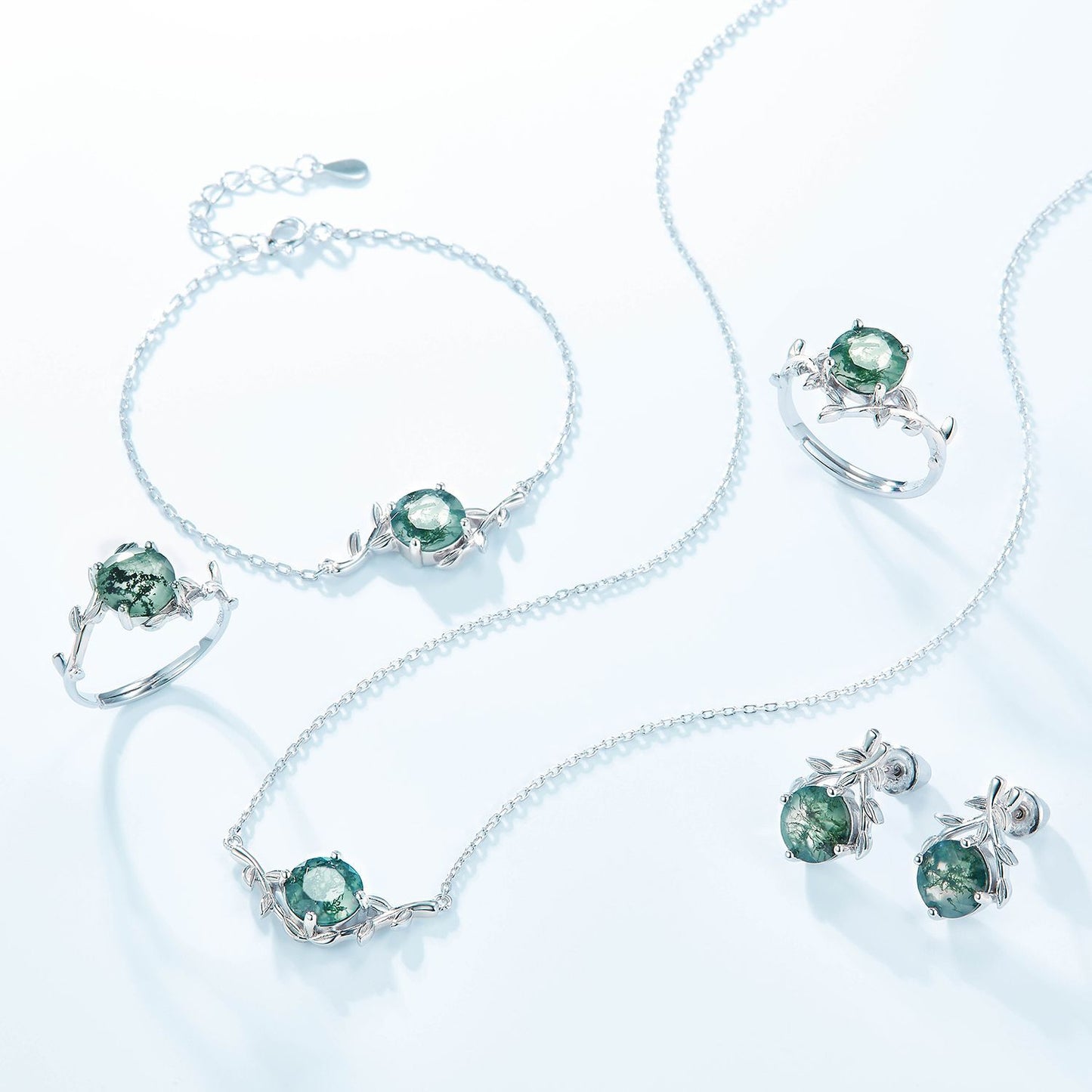 Silver jewelry set: Includes earrings, necklace, bracelets, rings, all with round moss agate and leaf - branch motifs, isolated on white.