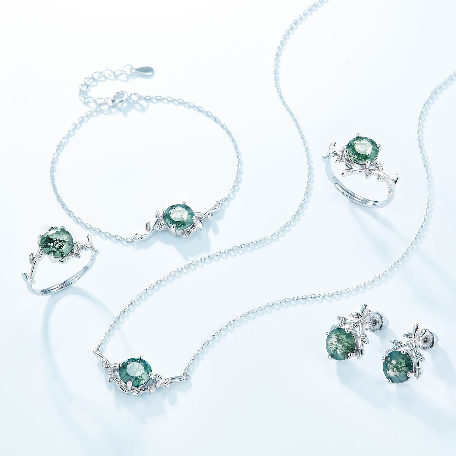 Silver jewelry set: Includes earrings, necklace, bracelets, rings, all with round moss agate and leaf - branch motifs, isolated on white.