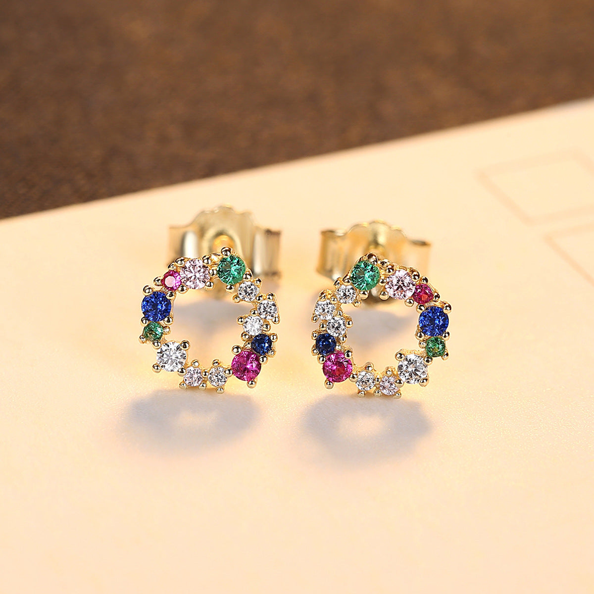 Colorful cubic zirconia earrings on a beige background