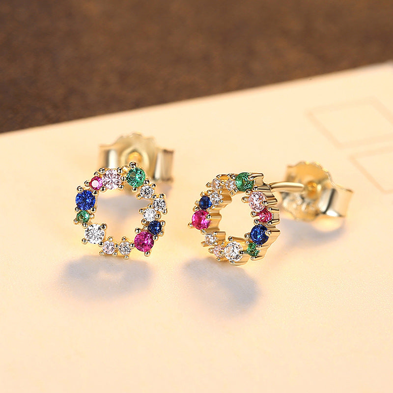 Yellow Gold earrings with colorful gemstones on a beige background