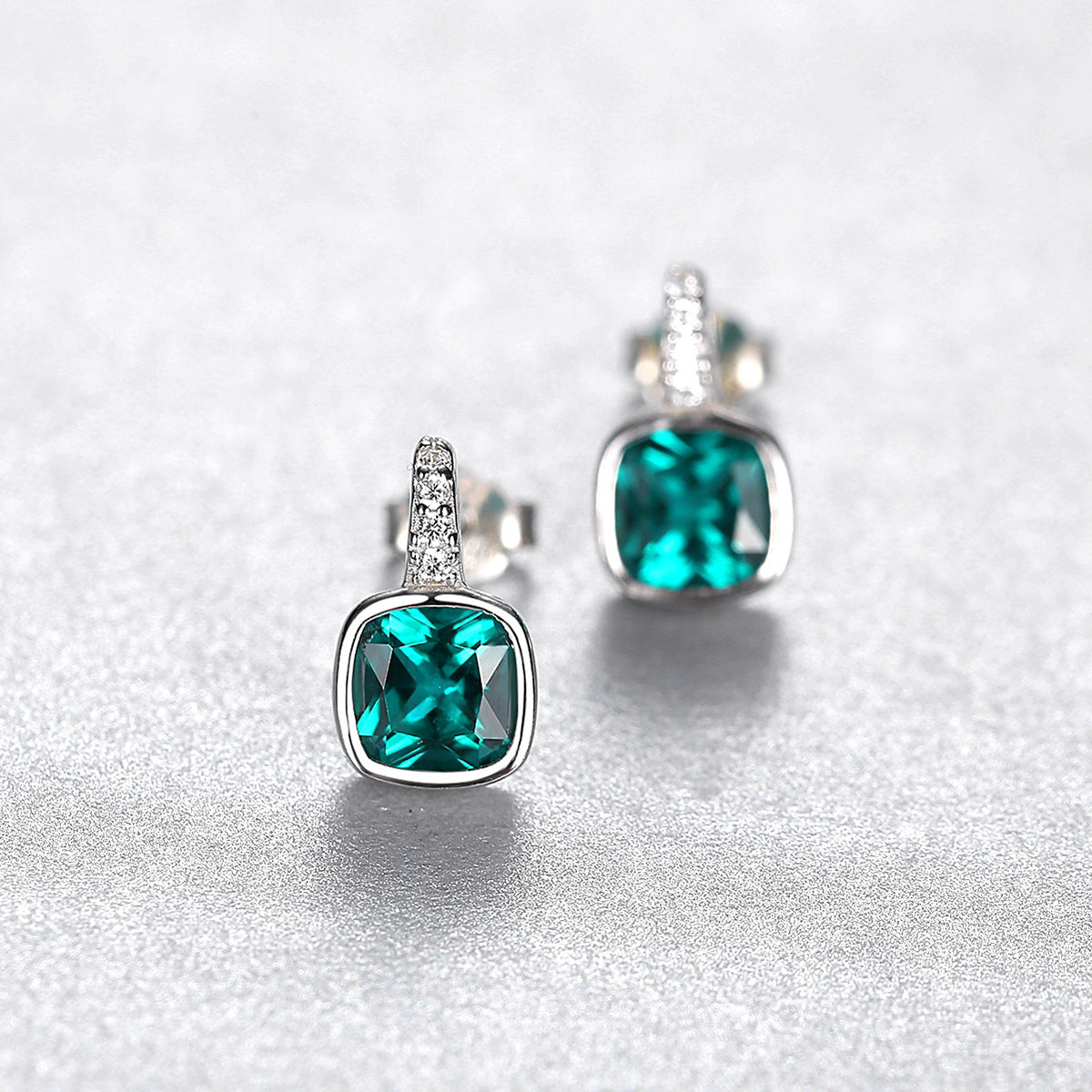 Pair of green gemstone earrings on a light gray background