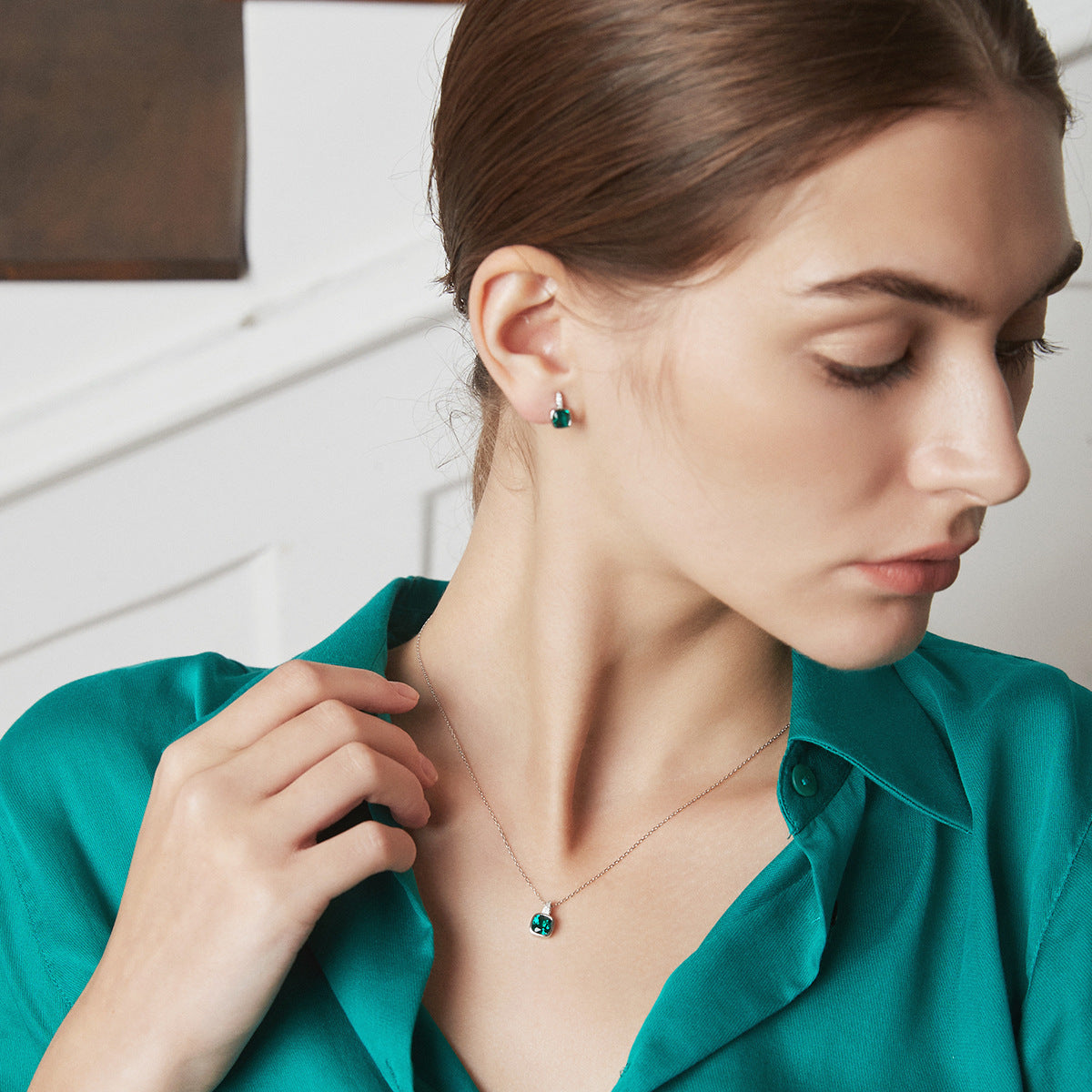 Woman wearing a necklace and earrings, with a neutral background