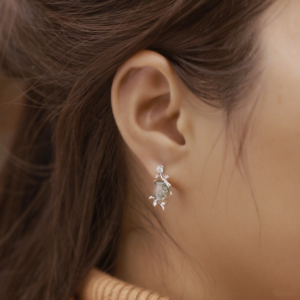 Silver stud earrings with rectangular moss agate, leaf - branch design, worn on an ear, elegant for nature - inspired style