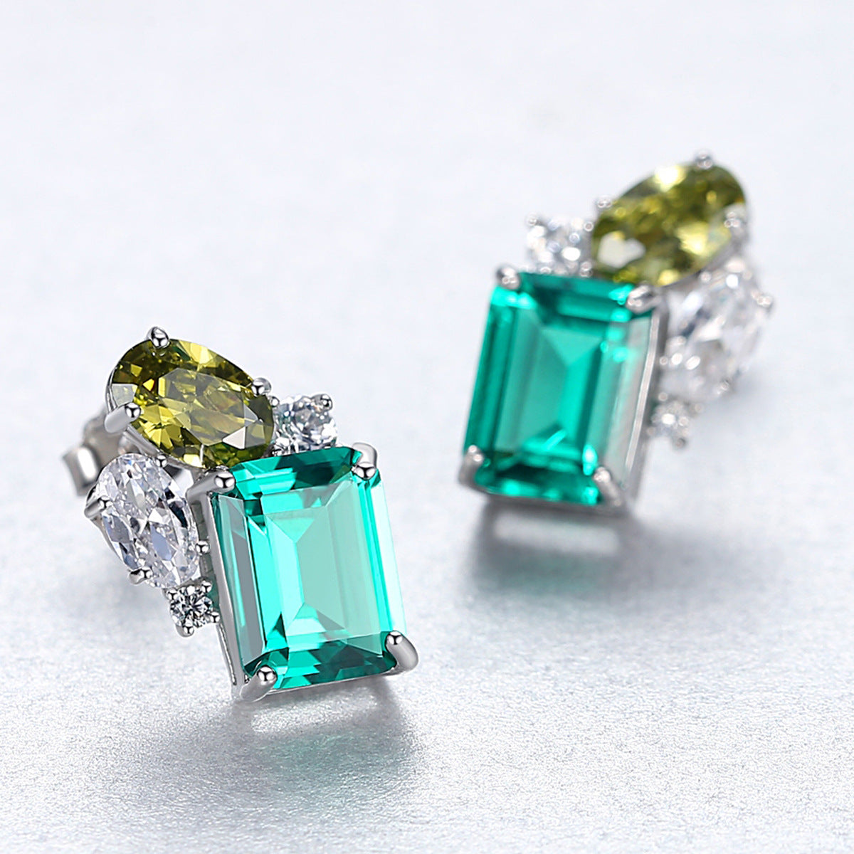 Pair of earrings with green gemstones on a light gray background