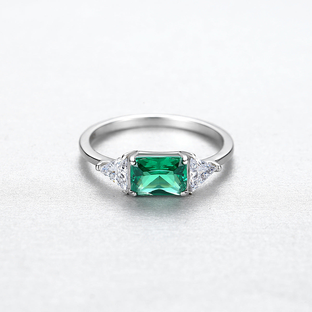 Silver ring with a green CZ set in east and west with 2 trillion cut clear CZ