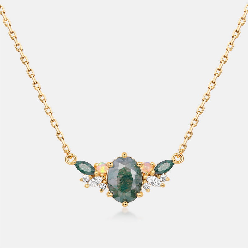 Gold necklace: Oval moss agate center, green gemstones, opals, and clear crystals, isolated on a white background.