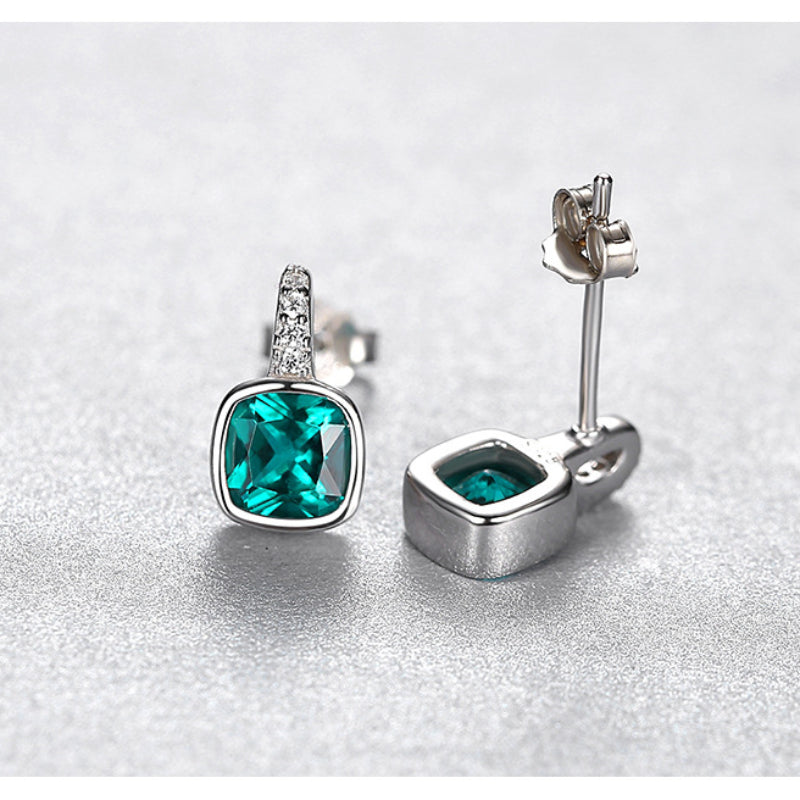 Silver earrings with green gemstones with butterfly backs on a light gray background