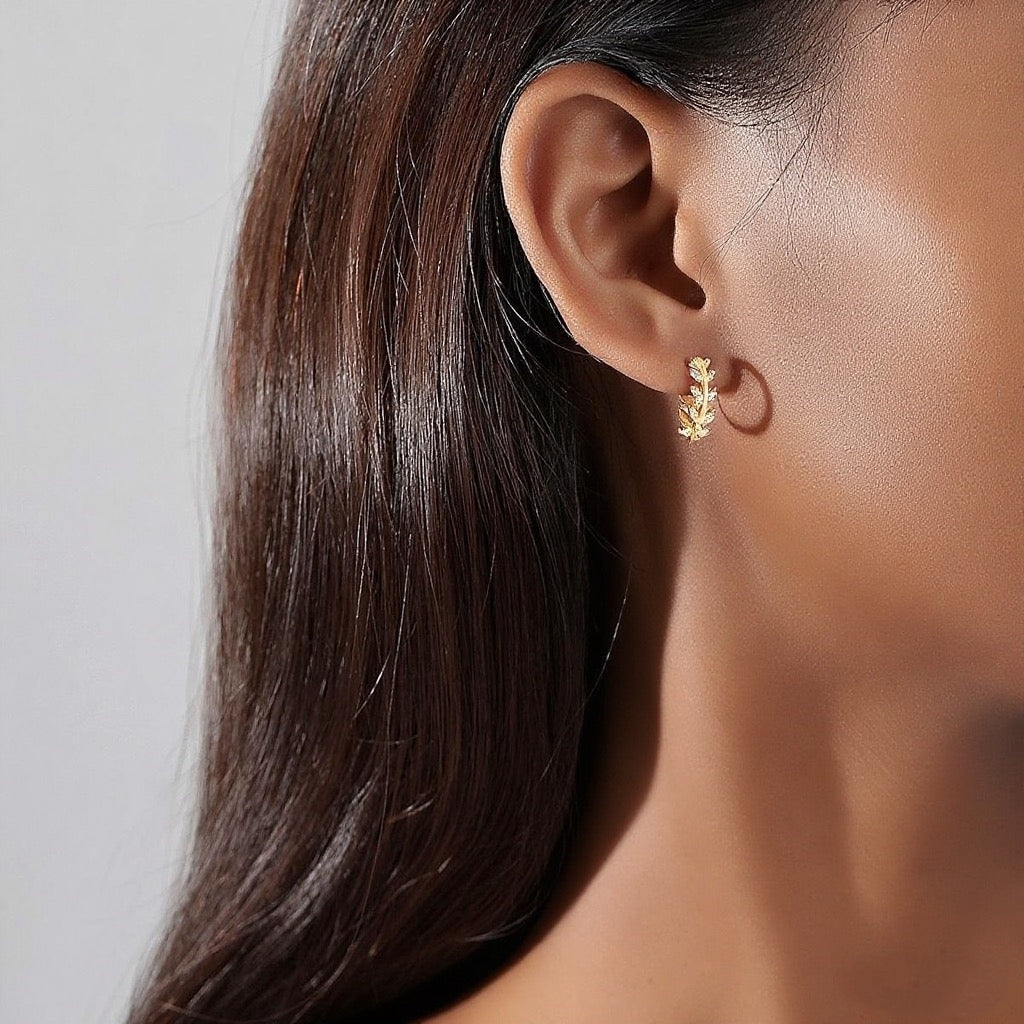Close-up of an ear wearing a gold earring with a blurred background