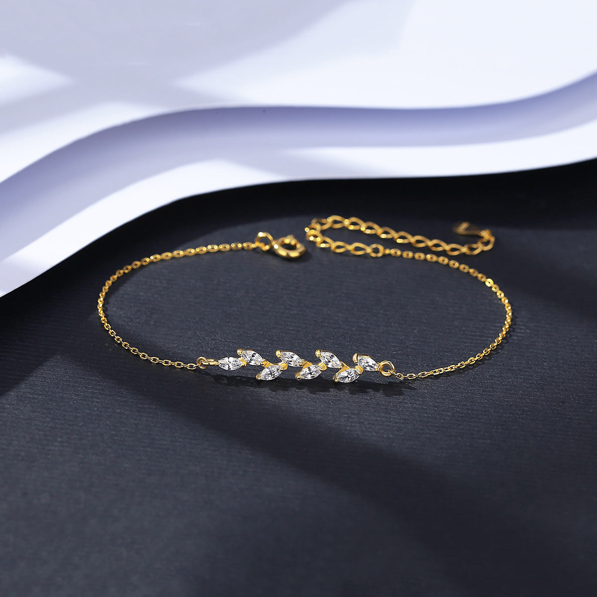 Gold bracelet with marquise CZ on a dark surface