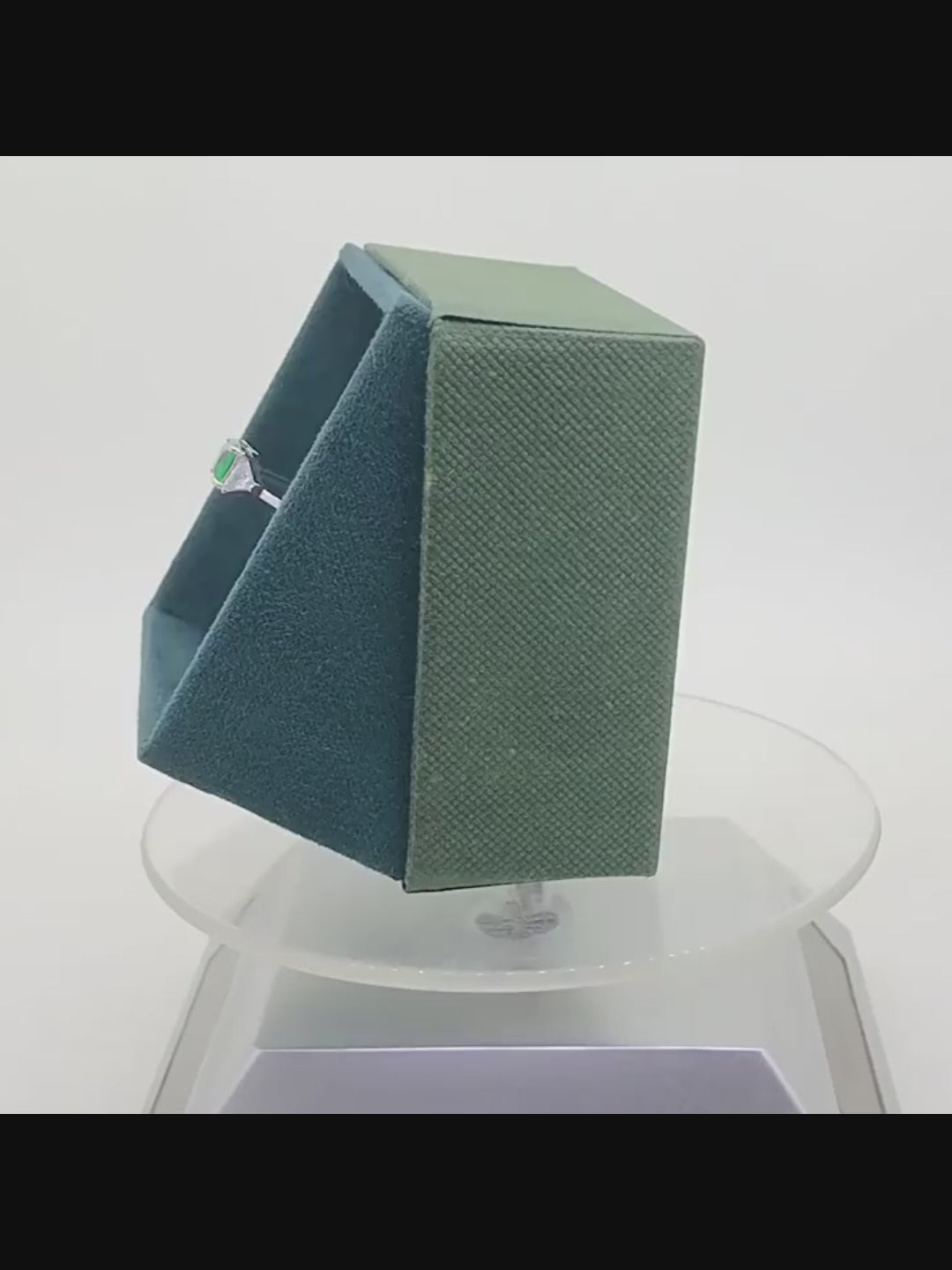 Emerald green CZ ring display in a green velvet box rotationally on desk