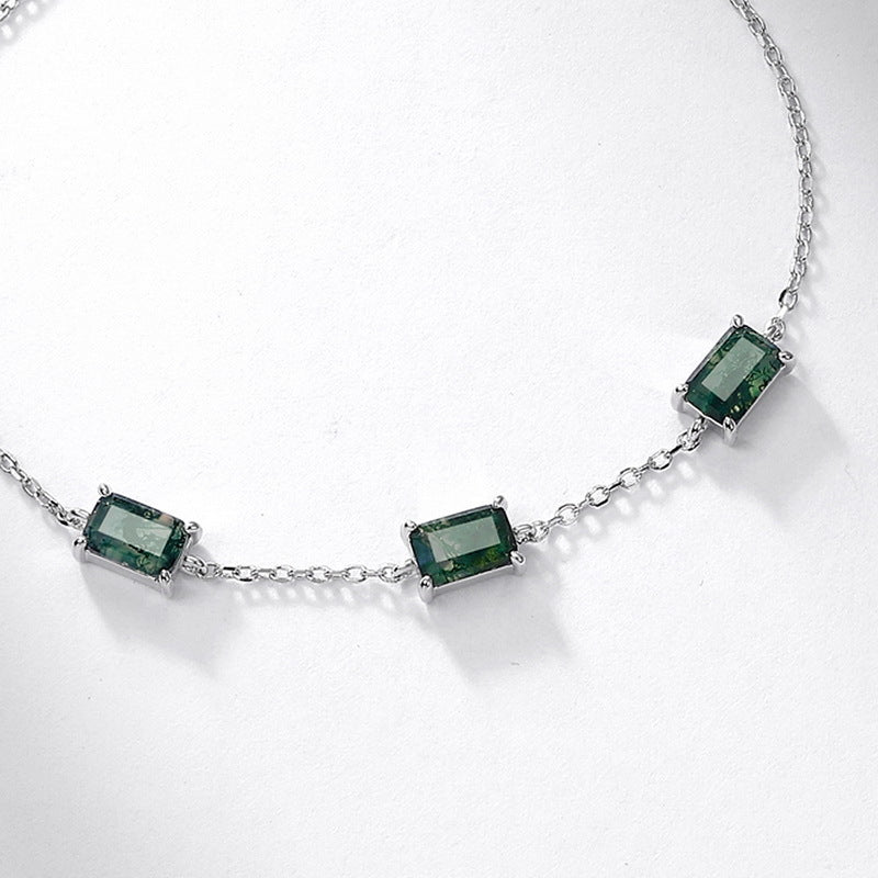 A silver chain necklace featuring three rectangular moss agate gemstones, each set in a four-prong setting and evenly spaced along the chain, displayed on a white background.